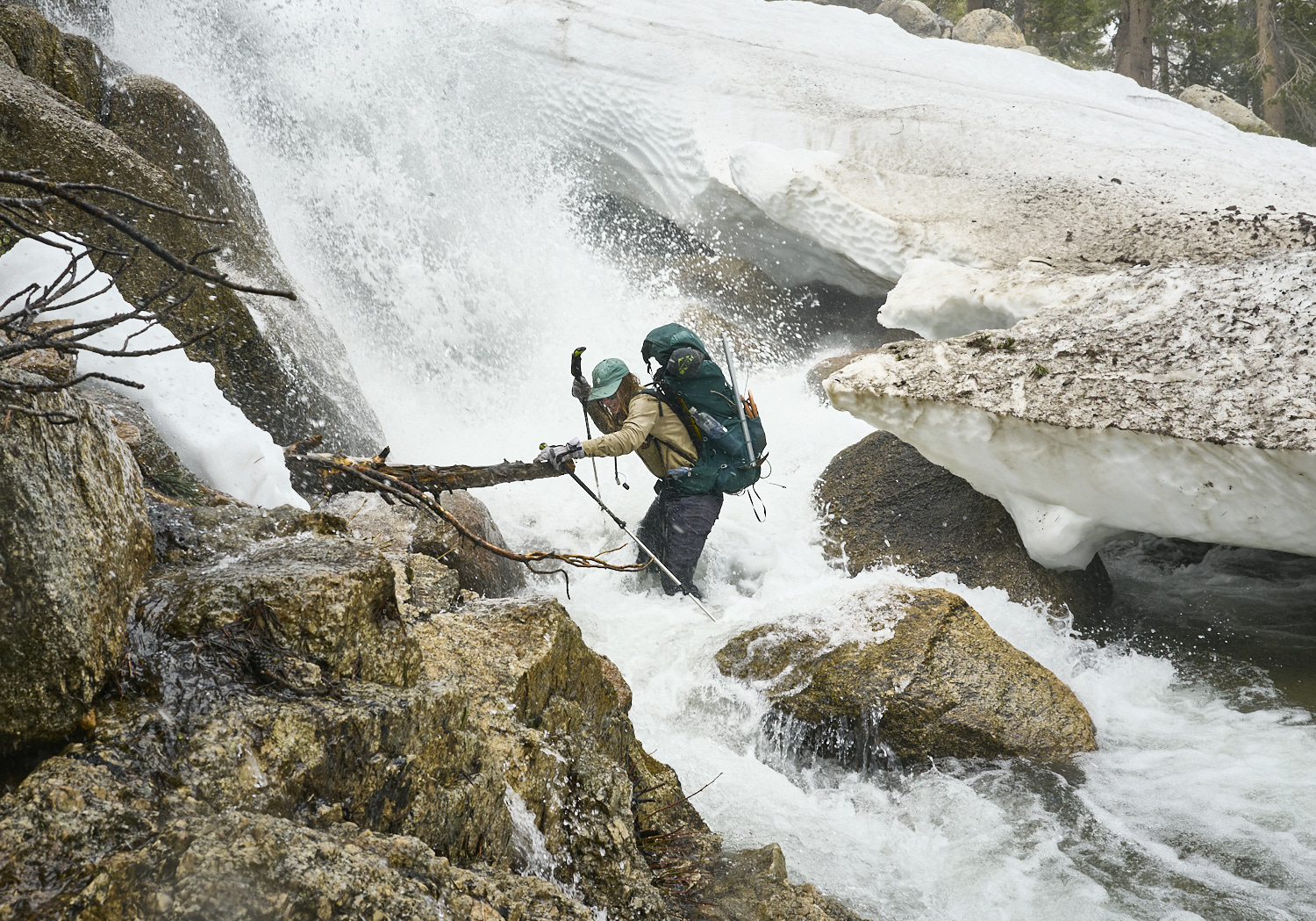 A hiker crosses Silver creek next to a raging waterfall.