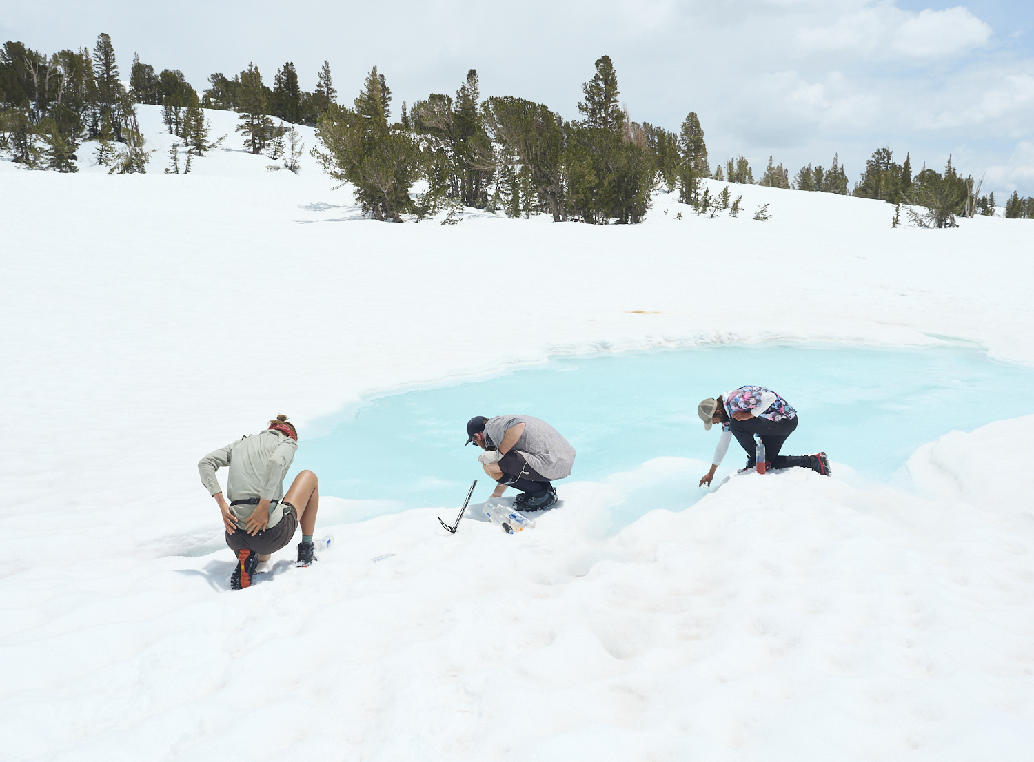 hikers are filling their bottles at a frozen lake