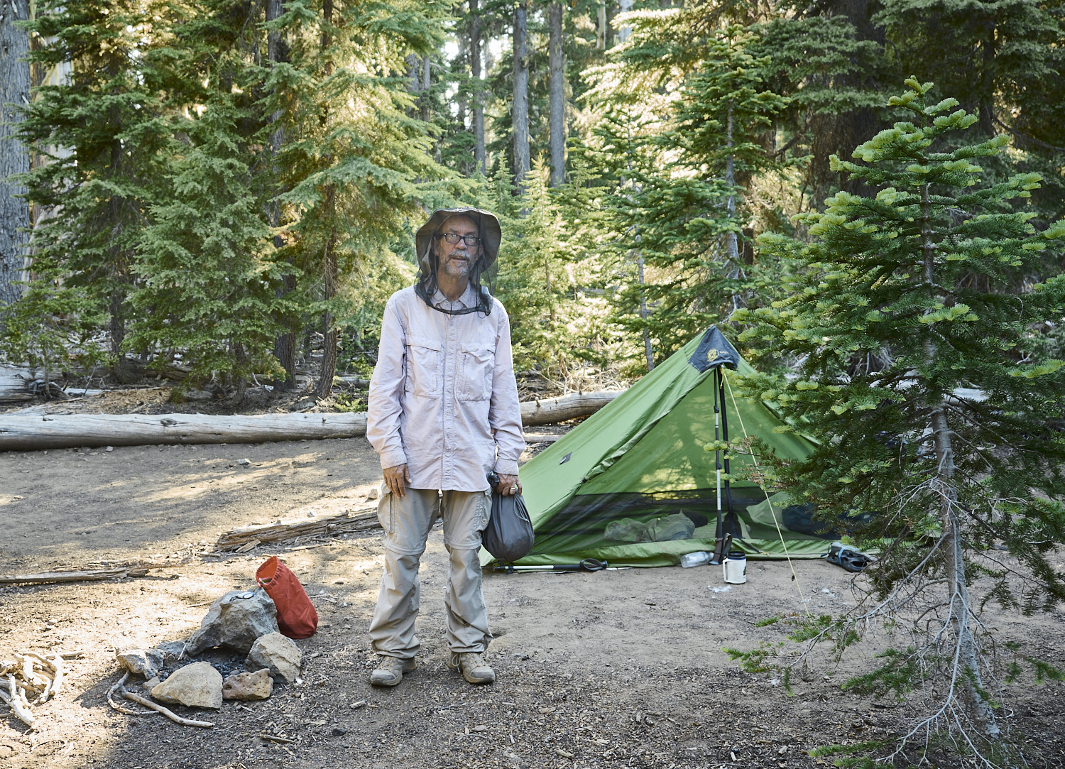 Bill from San Diego is wearing a mosquito net at his campsite in the evening.